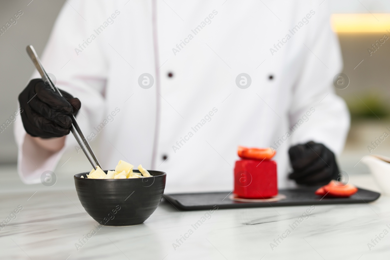 Confectioner decorating tasty dessert at white table in kitchen, selective focus Photo of Confectioner decorating tasty dessert at white table in kitchen, selective focus