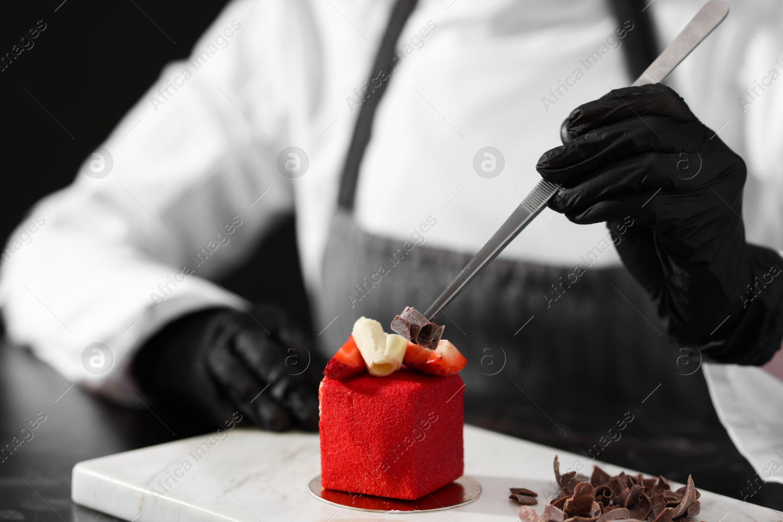 Confectioner decorating tasty dessert at black marble table in kitchen, closeup Photo of Confectioner decorating tasty dessert at black marble table in kitchen, closeup