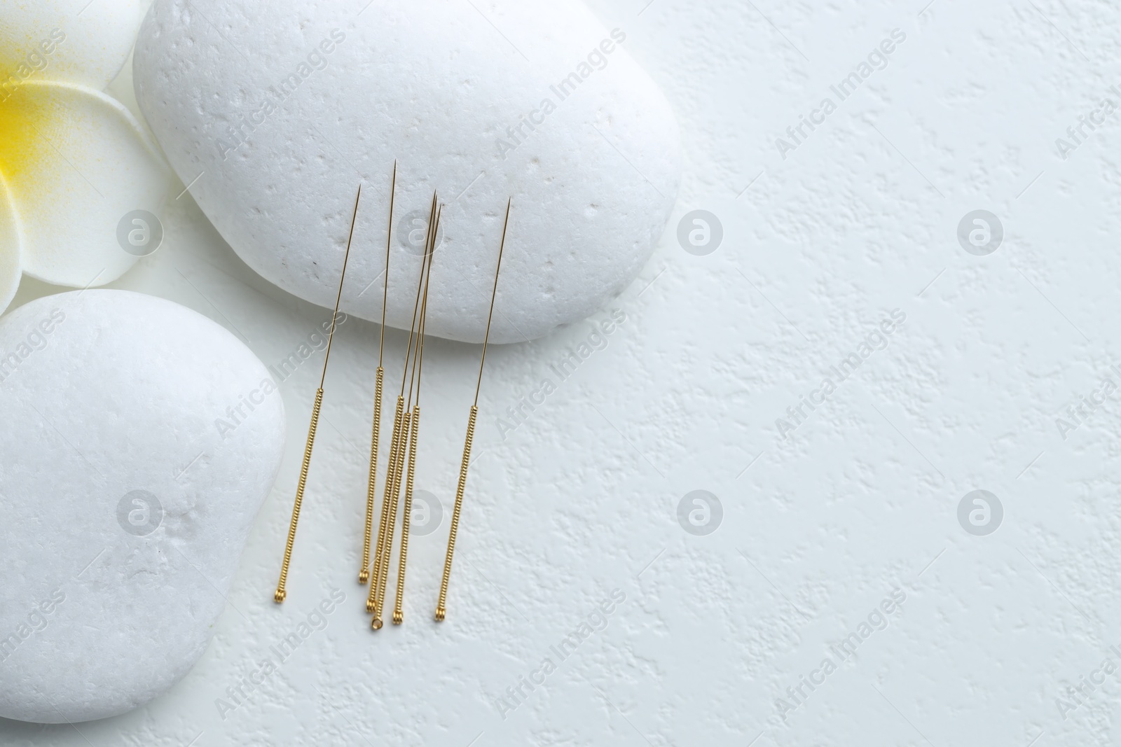 Acupuncture needles, spa stones and flower on white background, flat lay. Space for text Photo of Acupuncture needles, spa stones and flower on white background, flat lay. Space for text