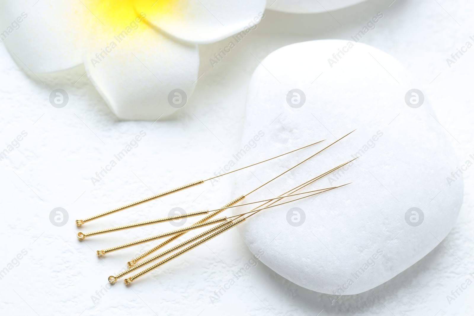 Acupuncture needles, spa stone and flower on white background, closeup Photo of Acupuncture needles, spa stone and flower on white background, closeup