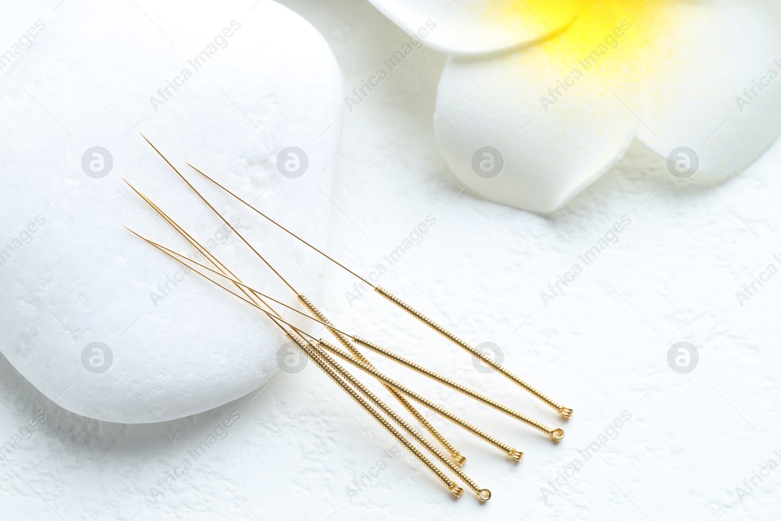 Acupuncture needles, spa stone and flower on white background, closeup Photo of Acupuncture needles, spa stone and flower on white background, closeup