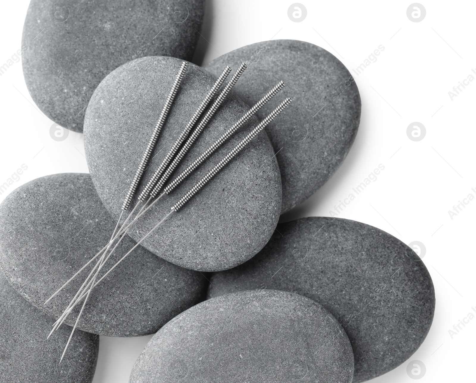 Acupuncture needles and spa stones on white background, flat lay Photo of Acupuncture needles and spa stones on white background, flat lay