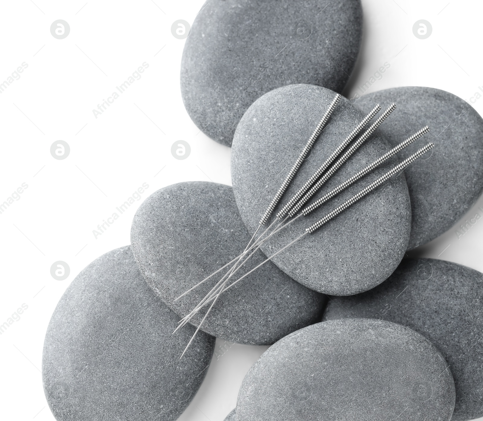 Acupuncture needles and spa stones on white background, flat lay Photo of Acupuncture needles and spa stones on white background, flat lay