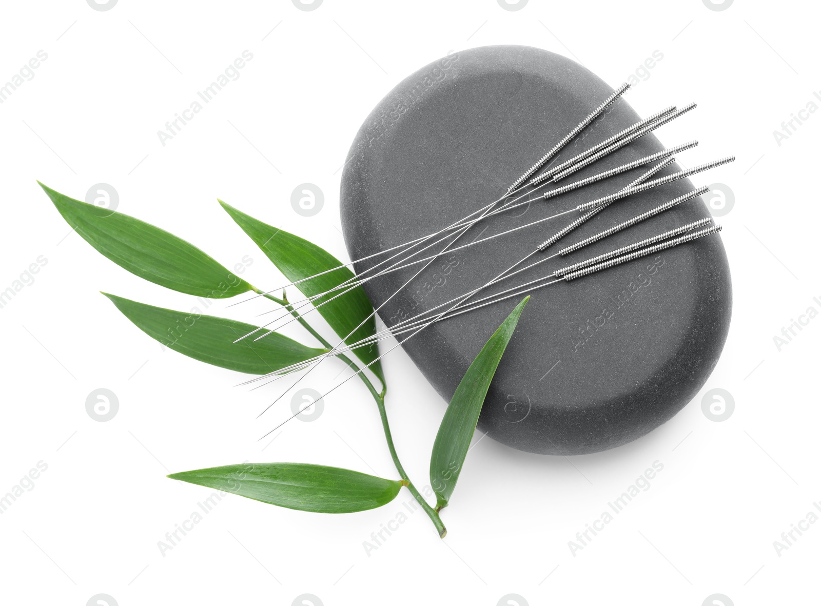 Acupuncture needles, spa stone and leaves isolated on white, top view Photo of Acupuncture needles, spa stone and leaves isolated on white, top view