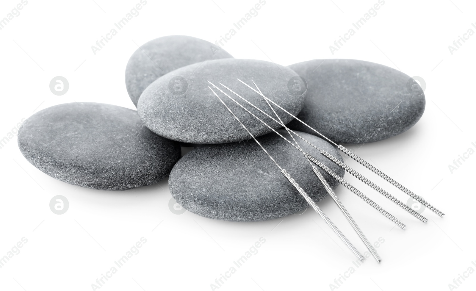Acupuncture needles and spa stones isolated on white Photo of Acupuncture needles and spa stones isolated on white