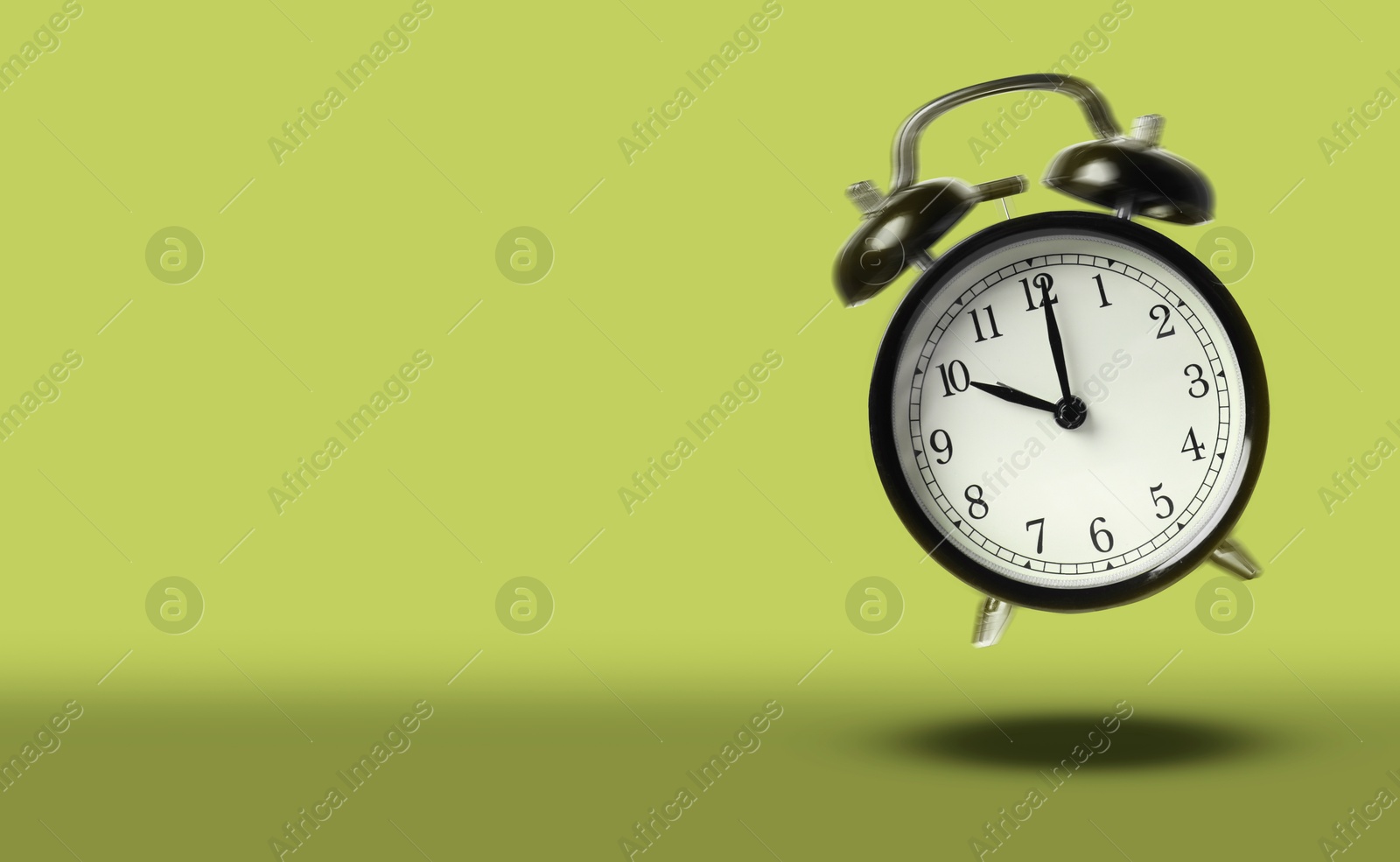 Black alarm clock ringing and jumping on olive color background. Banner design with space for text Image of Black alarm clock ringing and jumping on olive color background. Banner design with space for text