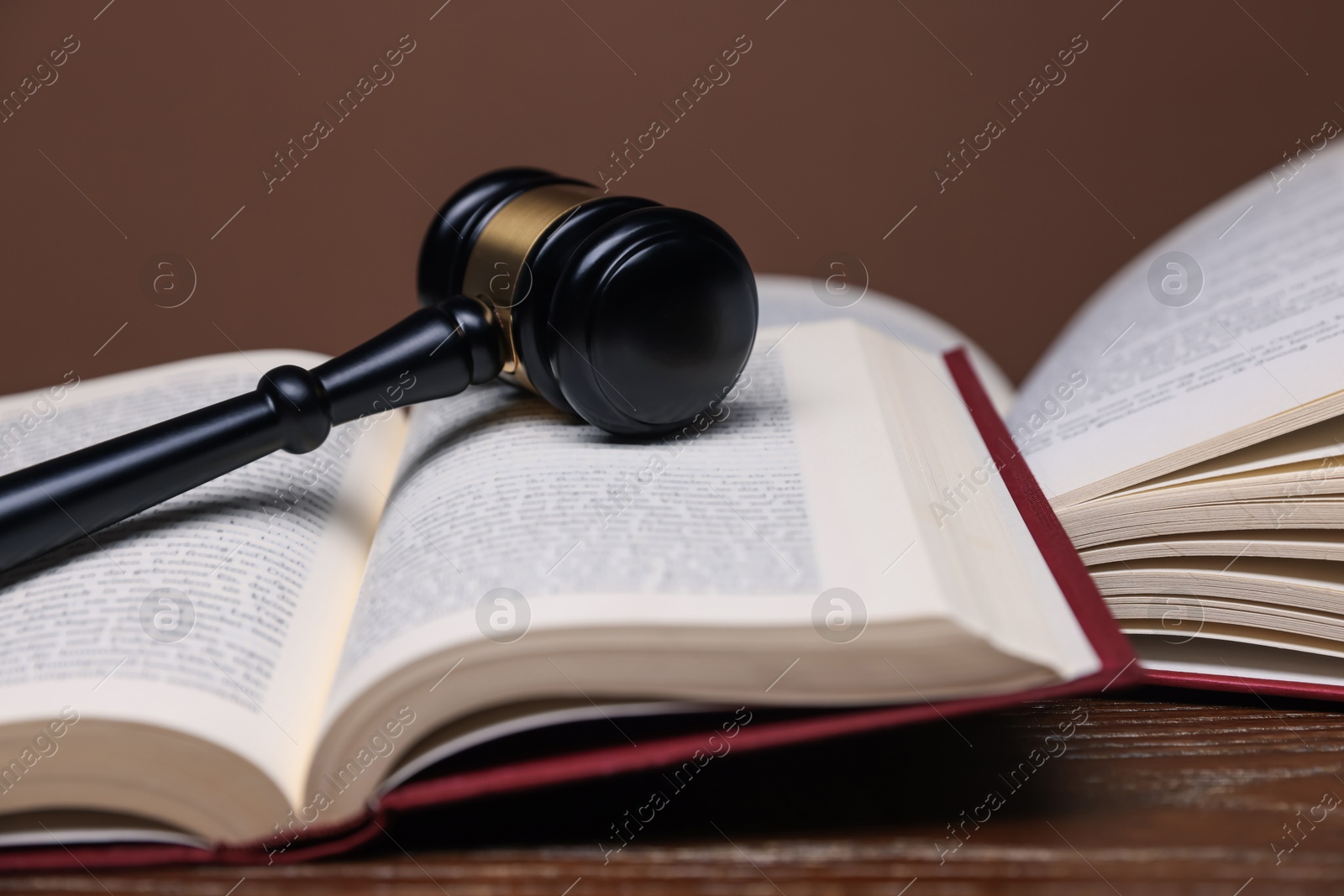 Judge's gavel and books on wooden table against brown background, closeup Photo of Judge's gavel and books on wooden table against brown background, closeup