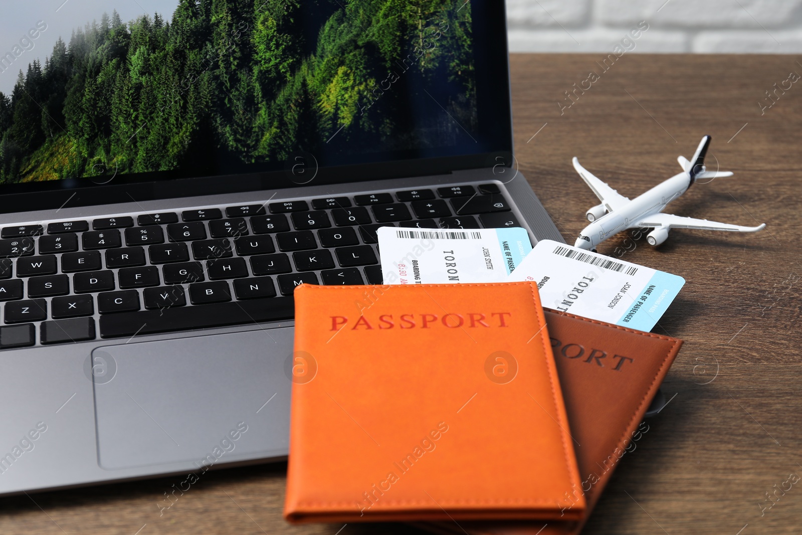 Passports, flight tickets, plane model and laptop on wooden table, closeup Photo of Passports, flight tickets, plane model and laptop on wooden table, closeup