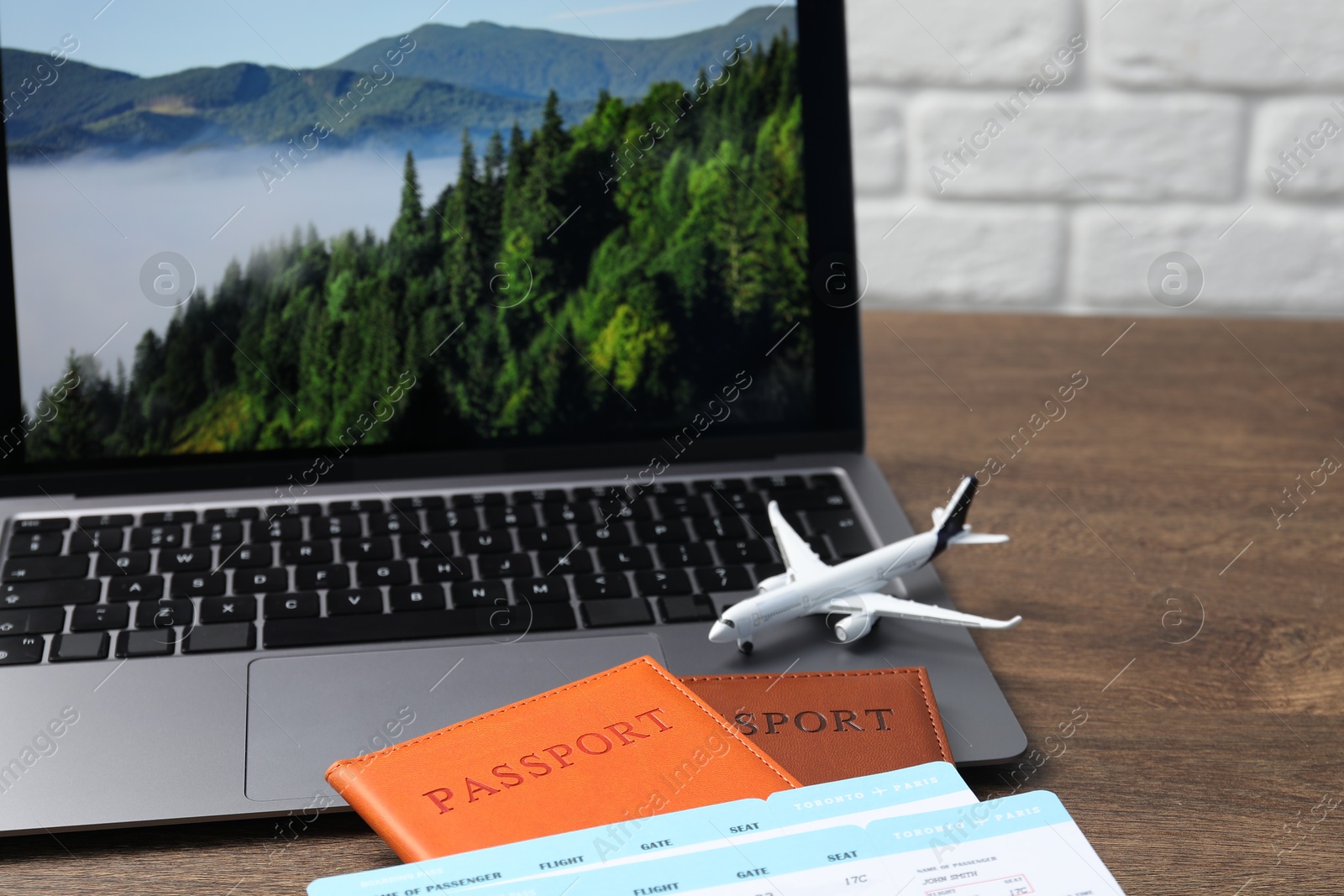 Passports, flight tickets, plane model and laptop on wooden table, closeup Photo of Passports, flight tickets, plane model and laptop on wooden table, closeup
