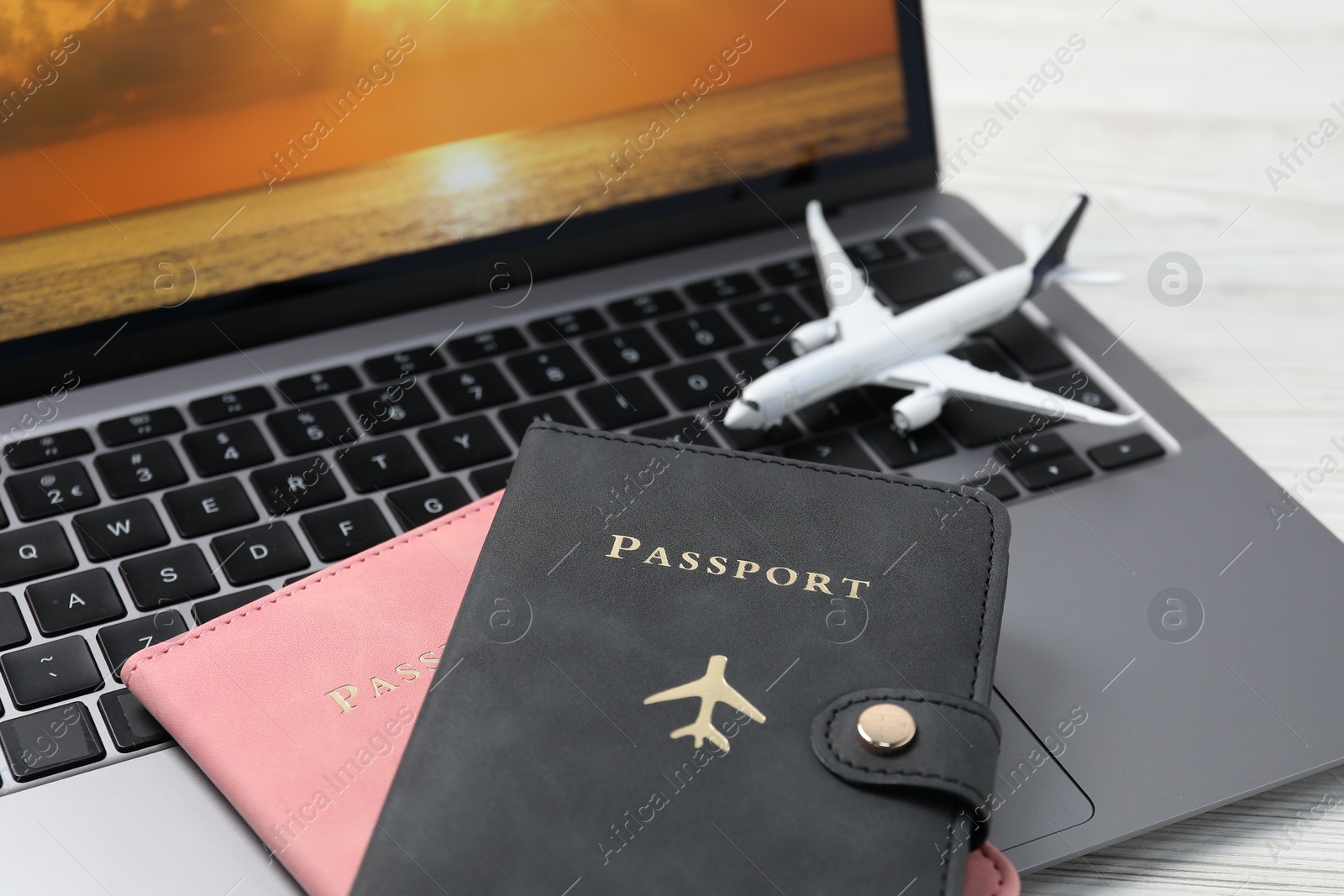Passports, plane model and laptop on table, closeup Photo of Passports, plane model and laptop on table, closeup