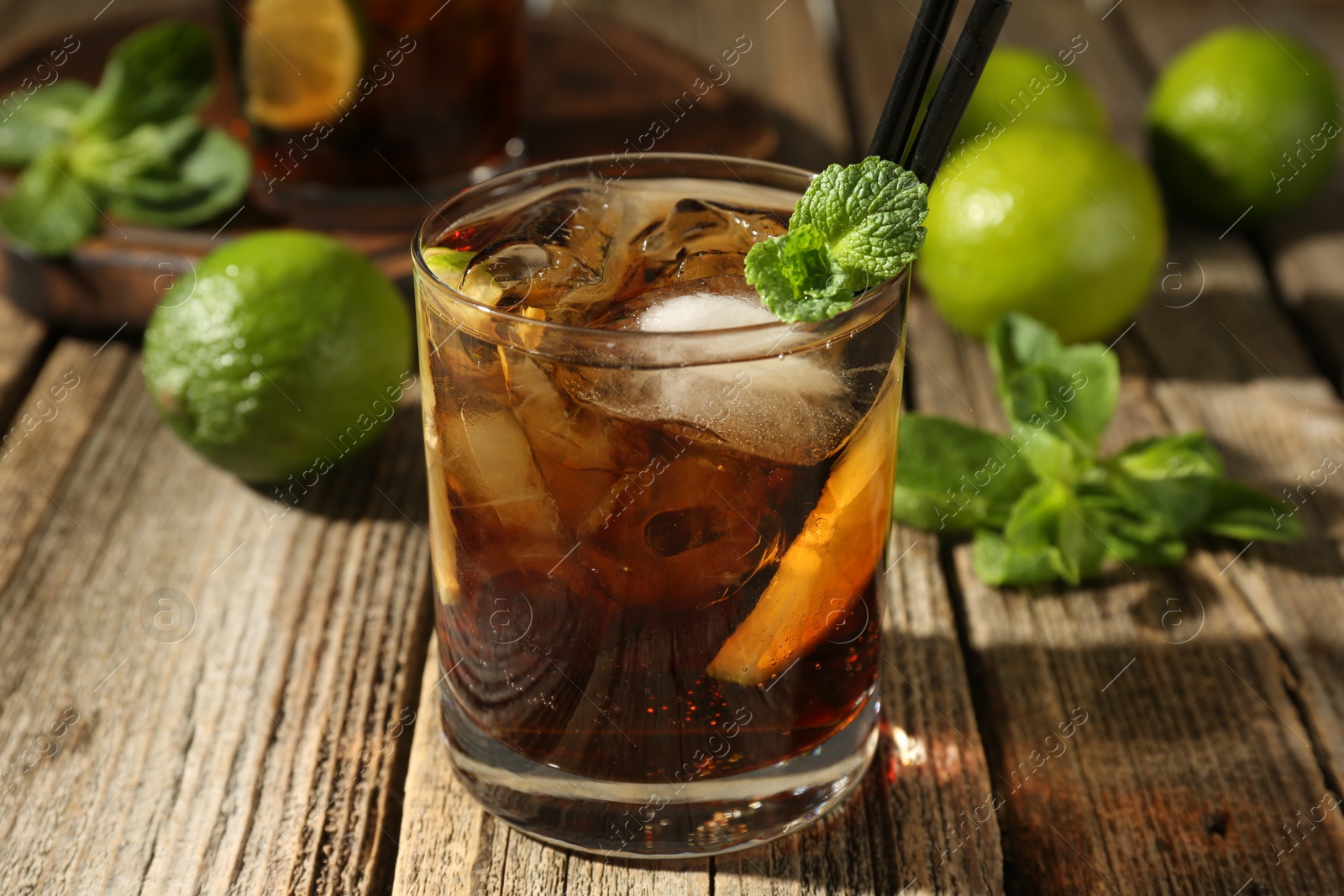 Refreshing Cuba libre cocktail with mint on wooden table, closeup Photo of Refreshing Cuba libre cocktail with mint on wooden table, closeup