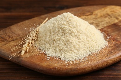 Photo of Pile of flour and spike on wooden table, closeup