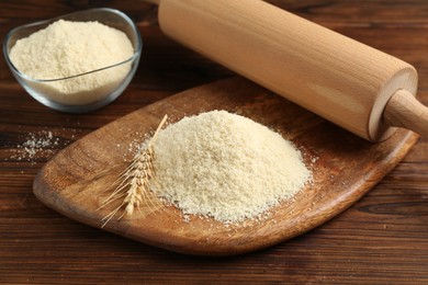 Photo of Pile of flour, spike and rolling pin on wooden table, closeup