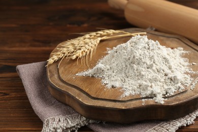 Photo of Pile of flour, spikes and rolling pin on wooden table, closeup