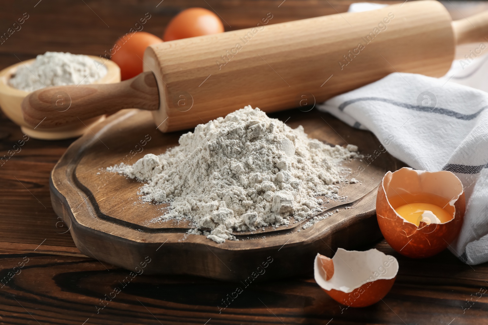 Pile of flour, eggs and rolling pin on wooden table, closeup Photo of Pile of flour, eggs and rolling pin on wooden table, closeup
