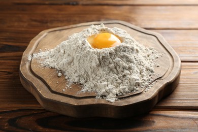 Photo of Pile of flour and egg on wooden table, closeup