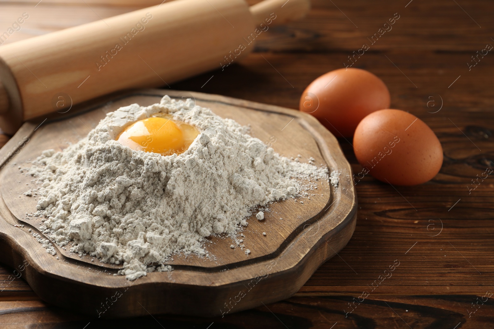 Pile of flour, eggs and rolling pin on wooden table, closeup Photo of Pile of flour, eggs and rolling pin on wooden table, closeup