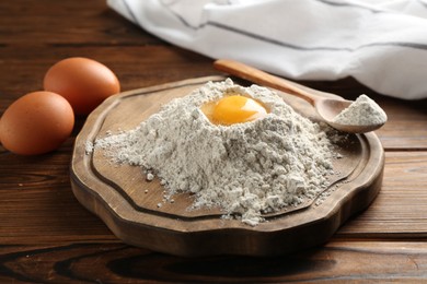 Photo of Pile of flour and eggs on wooden table, closeup