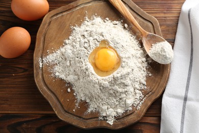 Photo of Pile of flour and eggs on wooden table, flat lay