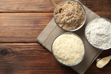 Photo of Different types of flour in bowls on wooden table, top view. Space for text