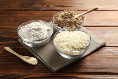 Photo of Different types of flour in bowls on wooden table