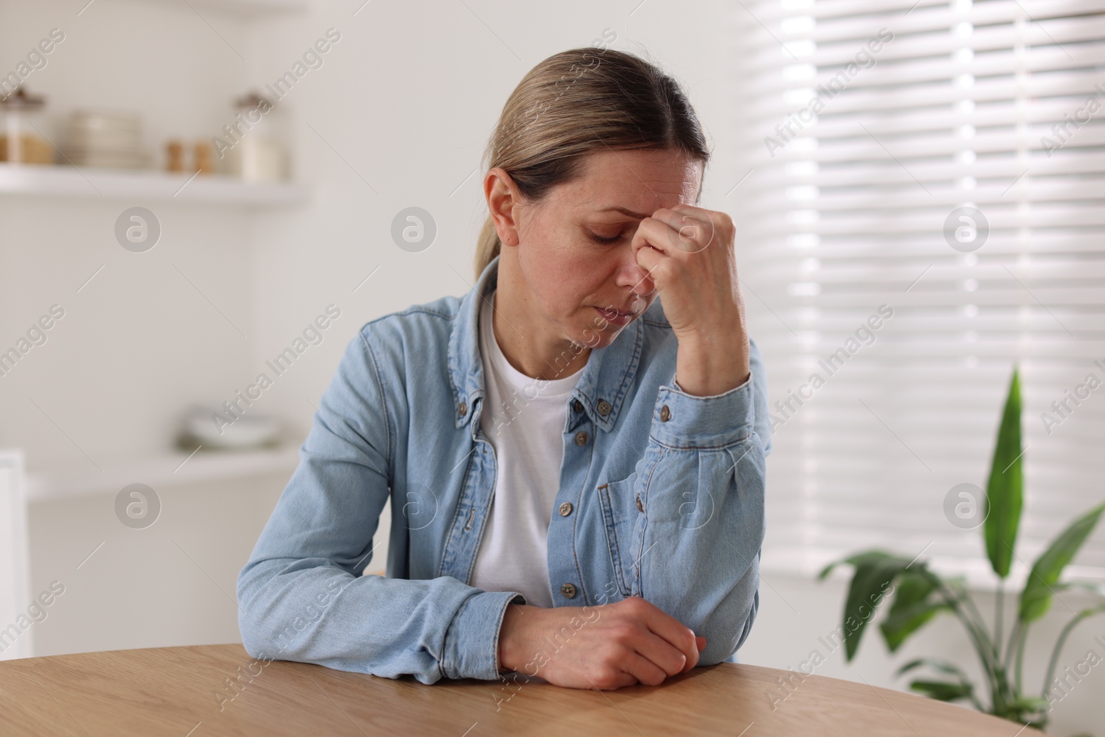 Depressed mature woman at table in room Photo of Depressed mature woman at table in room