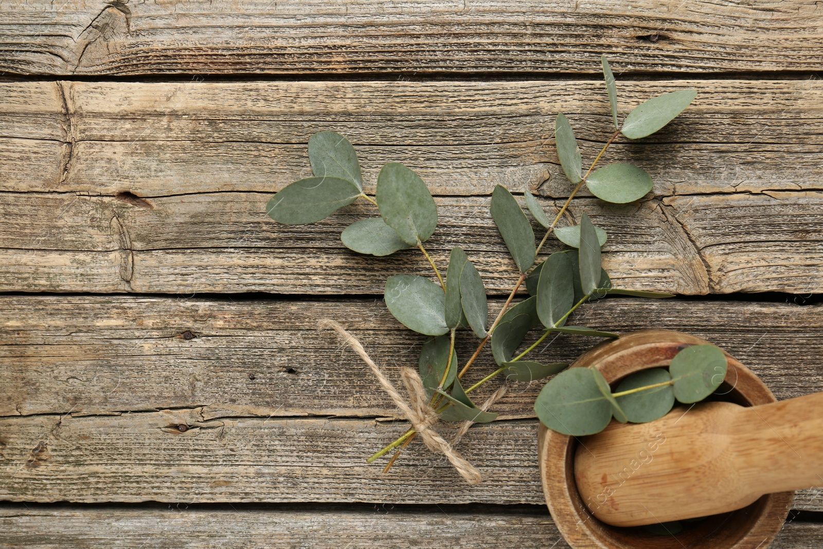 Beautiful eucalyptus branches, mortar and pestle on wooden background, top view Photo of Beautiful eucalyptus branches, mortar and pestle on wooden background, top view