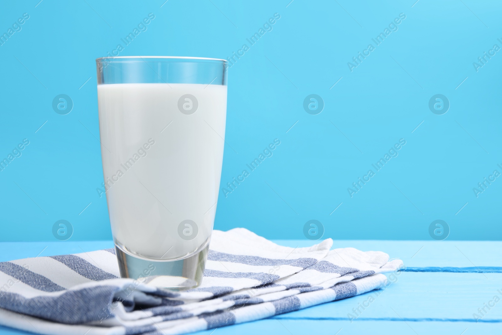 Fresh milk in glass on light blue wooden table. Space for text Photo of Fresh milk in glass on light blue wooden table. Space for text