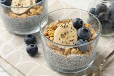 Photo of Delicious dessert with chia seeds, yogurt, granola, blueberries and banana on table, closeup. Superfood