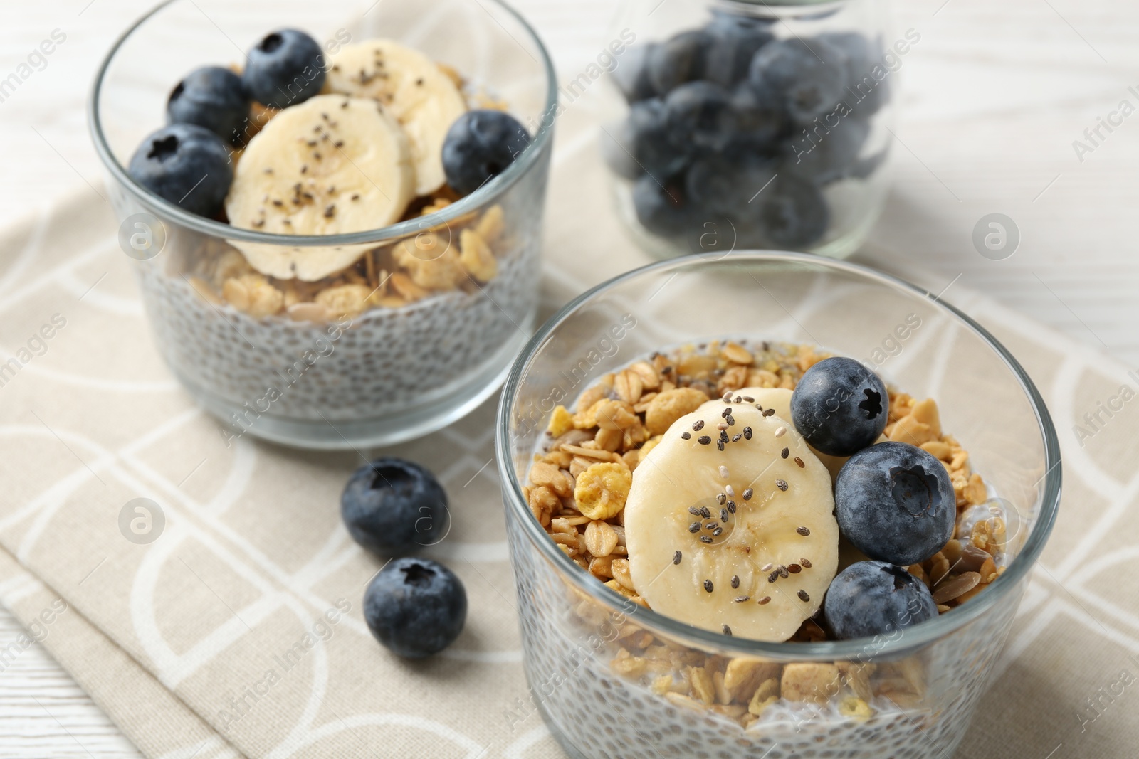 Delicious dessert with chia seeds, yogurt, granola, blueberries and banana on table, closeup. Superfood Photo of Delicious dessert with chia seeds, yogurt, granola, blueberries and banana on table, closeup. Superfood