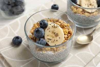 Photo of Delicious dessert with chia seeds, yogurt, granola, blueberries and banana on table, closeup. Superfood