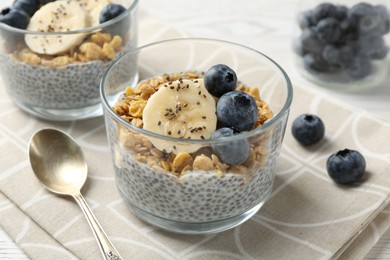 Photo of Delicious dessert with chia seeds, yogurt, granola, blueberries and banana on table, closeup. Superfood