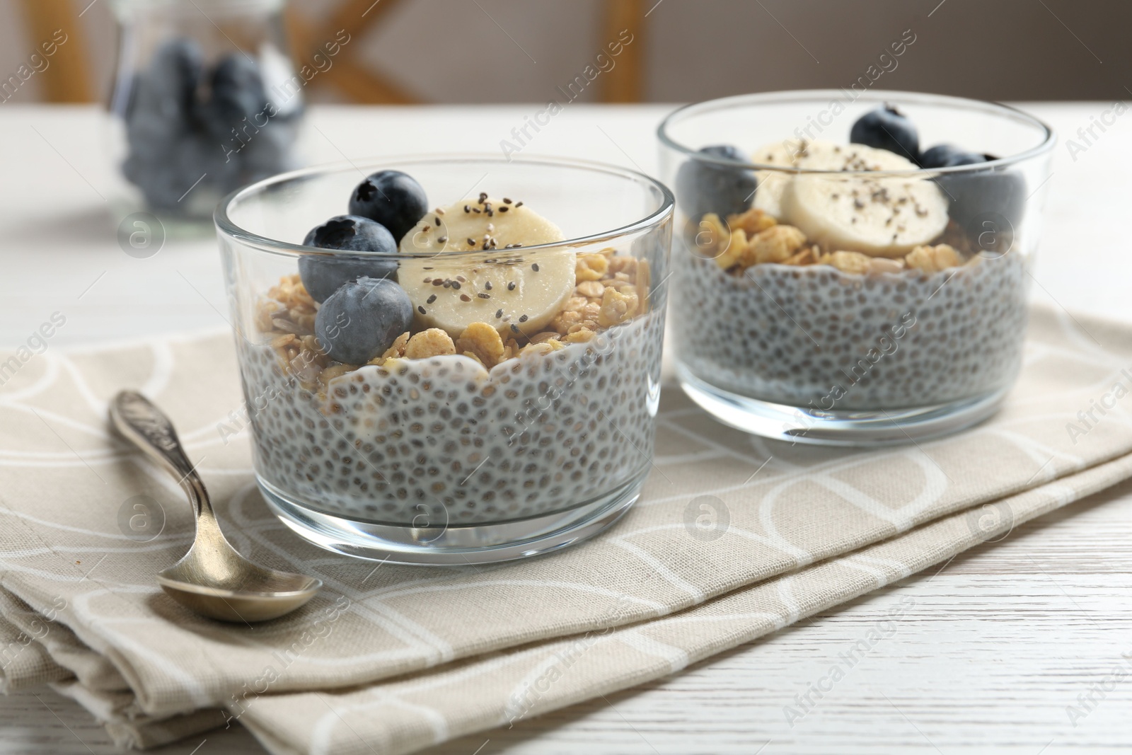 Delicious dessert with chia seeds, yogurt, granola, blueberries and banana on white wooden table, closeup. Superfood Photo of Delicious dessert with chia seeds, yogurt, granola, blueberries and banana on white wooden table, closeup. Superfood