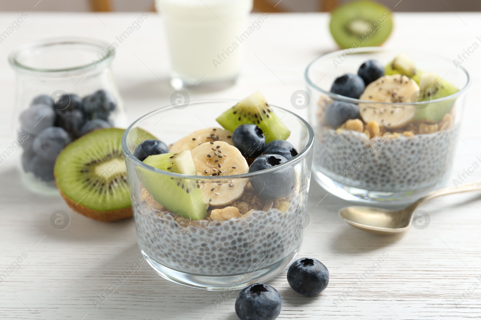 Delicious dessert with chia seeds, yogurt, granola, blueberries, banana and kiwi on white wooden table, closeup. Superfood Photo of Delicious dessert with chia seeds, yogurt, granola, blueberries, banana and kiwi on white wooden table, closeup. Superfood
