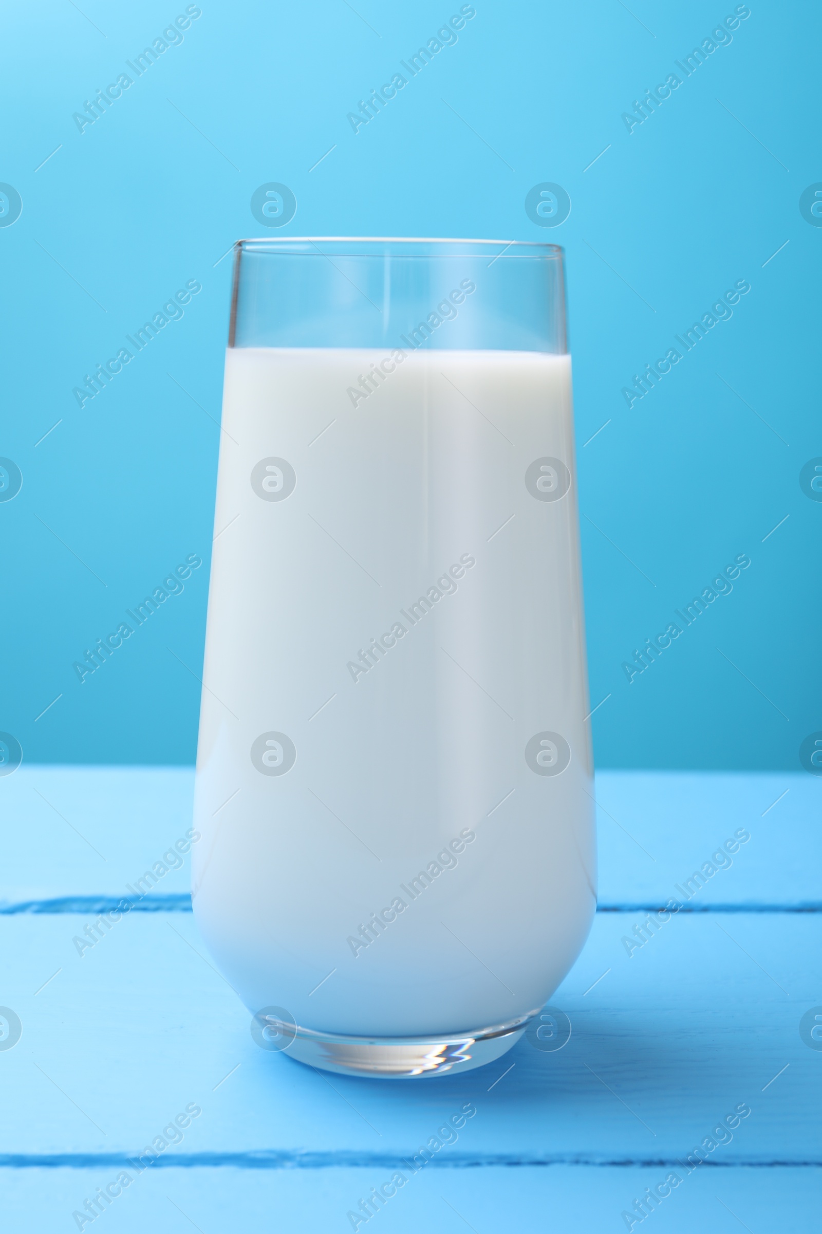 Fresh milk in glass on light blue wooden table, closeup Photo of Fresh milk in glass on light blue wooden table, closeup