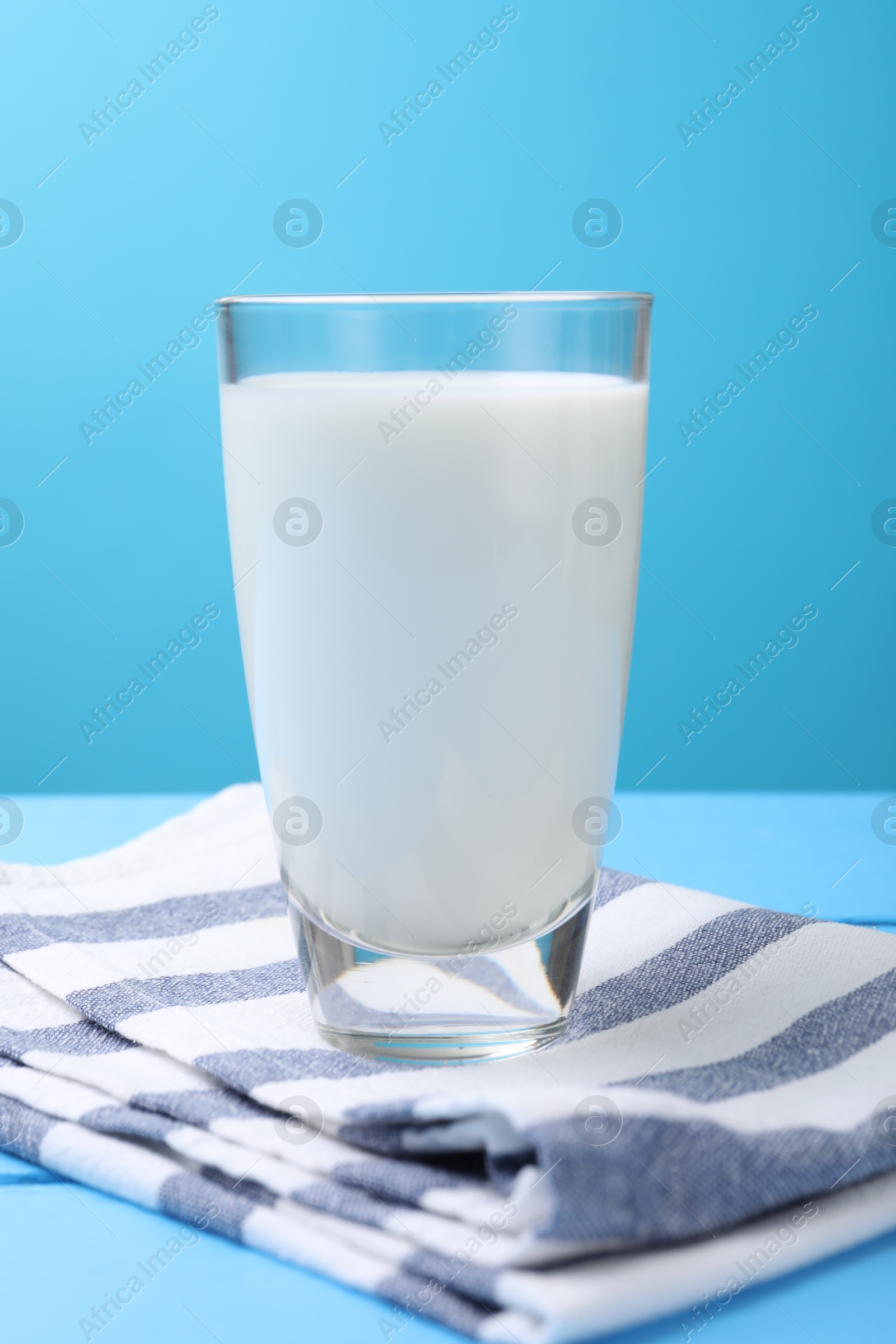 Fresh milk in glass on light blue wooden table Photo of Fresh milk in glass on light blue wooden table