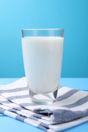 Photo of Fresh milk in glass on light blue wooden table