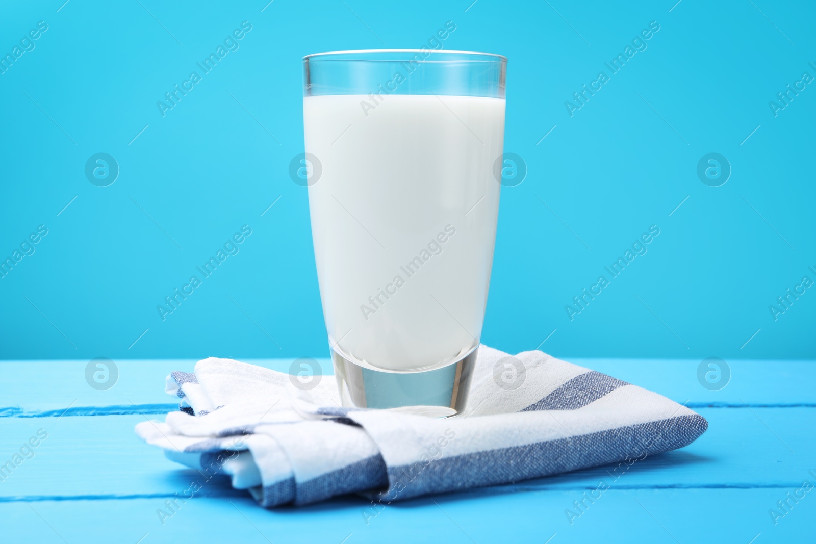 Fresh milk in glass on light blue wooden table Photo of Fresh milk in glass on light blue wooden table