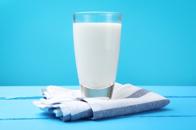 Photo of Fresh milk in glass on light blue wooden table