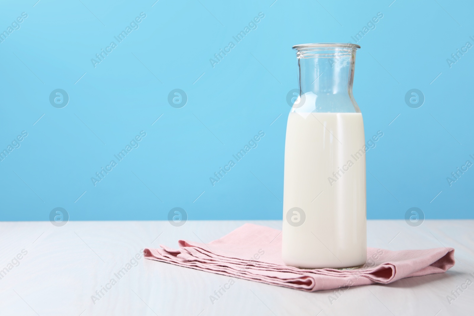 Fresh milk in jug on white wooden table against light blue background. Space for text Photo of Fresh milk in jug on white wooden table against light blue background. Space for text