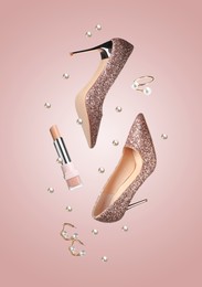 Image of Fashionable shoes, lipstick, jewelry and pearls in air on pink background