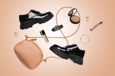 Image of Fashionable shoes, makeup products and accessories in air on dark beige background