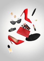 Image of Fashionable shoes, makeup products and accessories in air on grey background