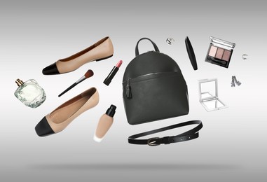 Image of Fashionable shoes, makeup products and accessories in air on grey background