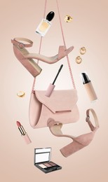Image of Fashionable shoes, makeup products and accessories in air on pink beige background