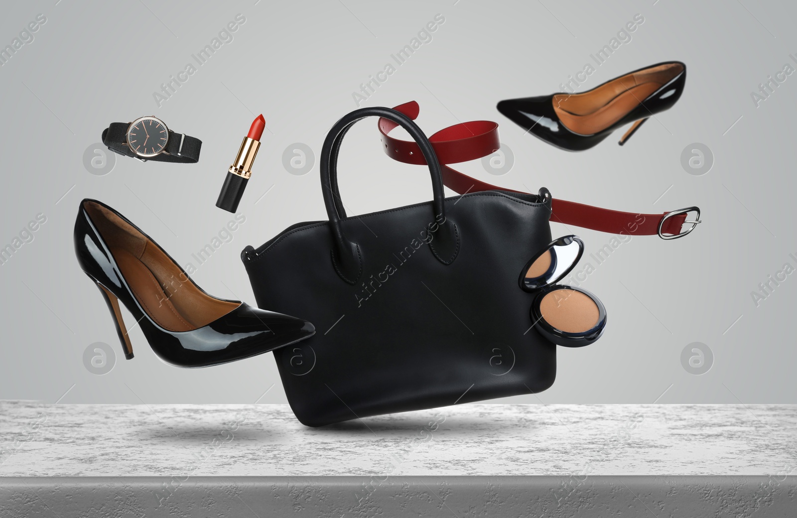 Fashionable shoes, makeup products and accessories falling onto table against light grey background Image of Fashionable shoes, makeup products and accessories falling onto table against light grey background