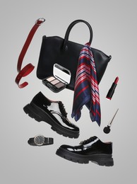 Image of Fashionable shoes, makeup products and accessories in air on light grey background