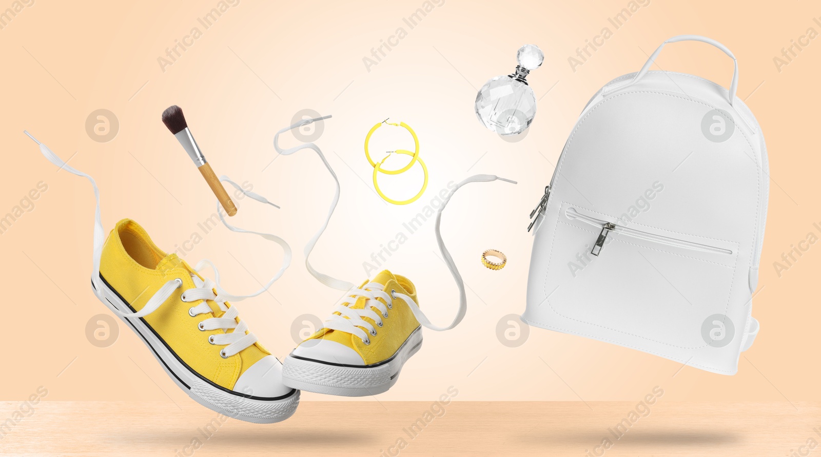 Fashionable shoes and accessories falling onto table against beige background Image of Fashionable shoes and accessories falling onto table against beige background