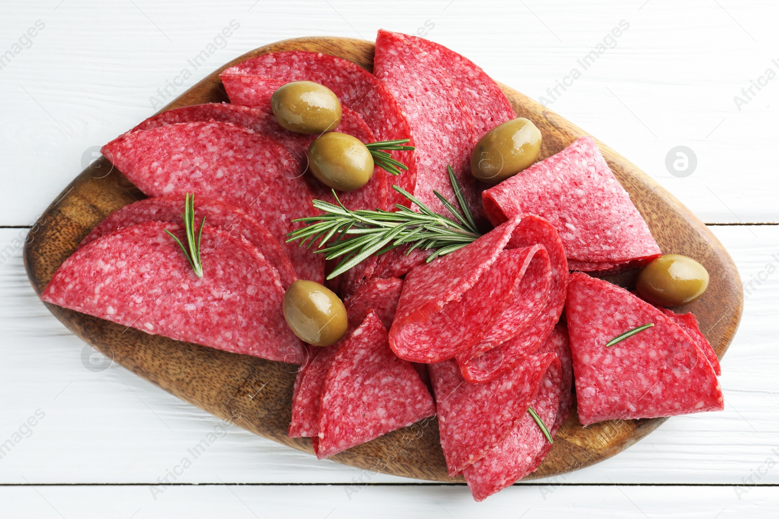 Photo of Slices of delicious sausage with olives and rosemary served on white wooden table, top view