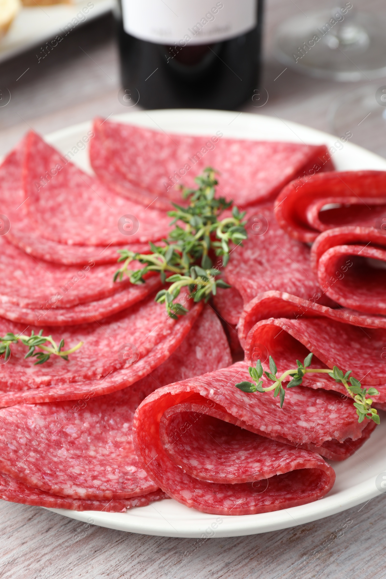 Slices of delicious sausage with thyme served on light wooden table, closeup Photo of Slices of delicious sausage with thyme served on light wooden table, closeup